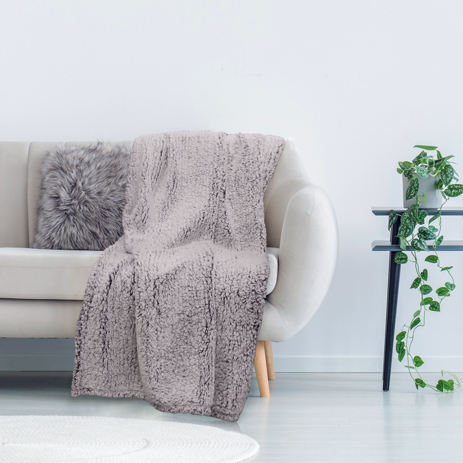 Plaid Sherpa gris confort ultime ZenPur posé sur un canapé, couverture douce et moelleuse pour détente et ambiance cosy