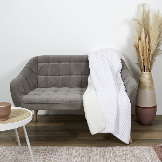 Plaid ZenPur en flanelle côtelée et Sherpa écru posé sur un canapé moderne pour confort et décoration