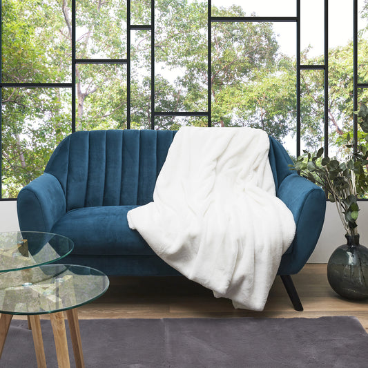 Plaid ZenPur opulent en fausse fourrure écru posé sur un canapé moderne pour confort et décoration