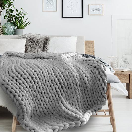 Plaid chunky grosse maille posé sur un lit, jeté décoratif chaleureux et cosy